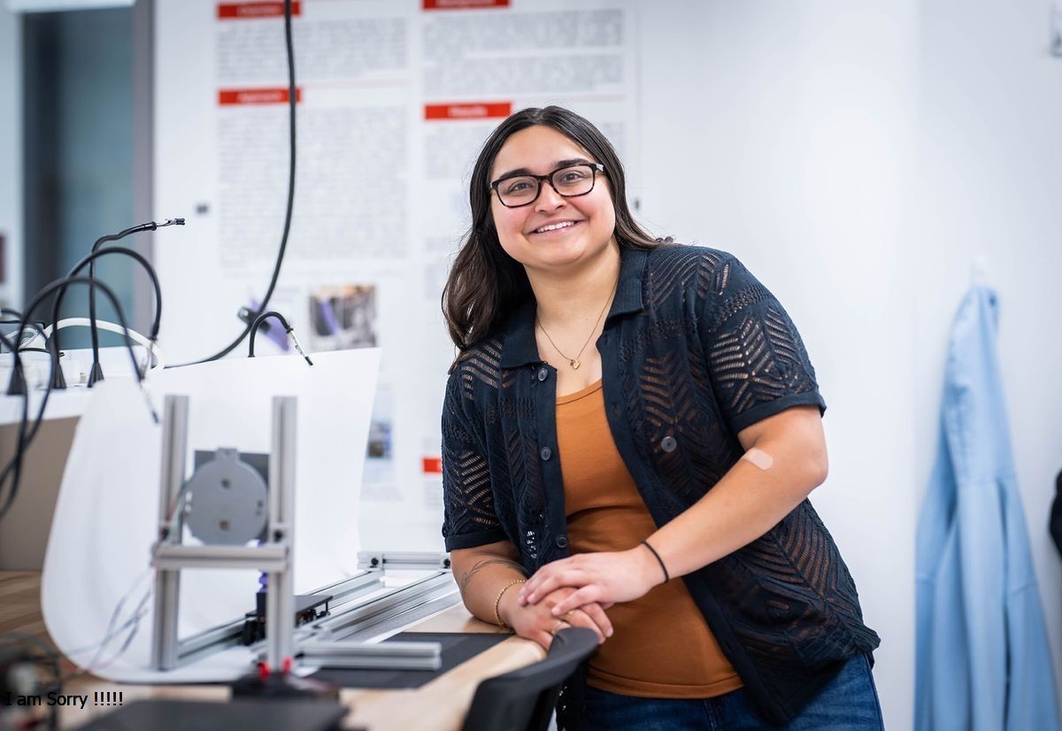 Photo: A woman with dark hair and glasses smiling and posing in a lab